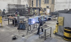 Soldador trabajando en una estructura metálica en el taller de Talleres Matico, empresa especializada en herrería general y artística